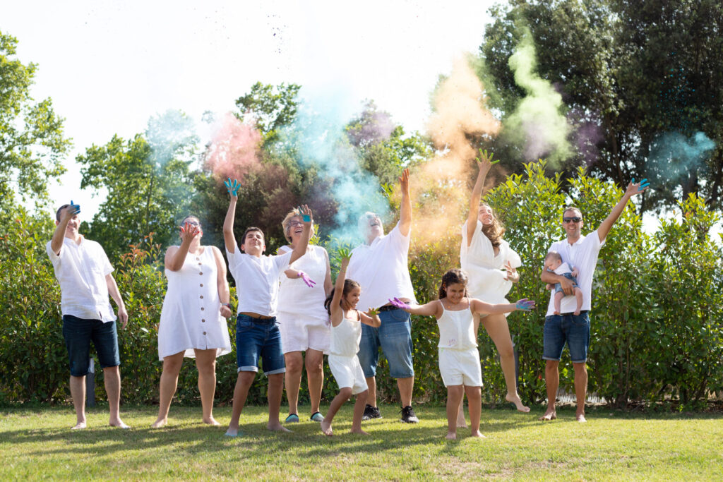 Familia lanzando polvos de colores durante una sesión fotográfica divertida en el campo