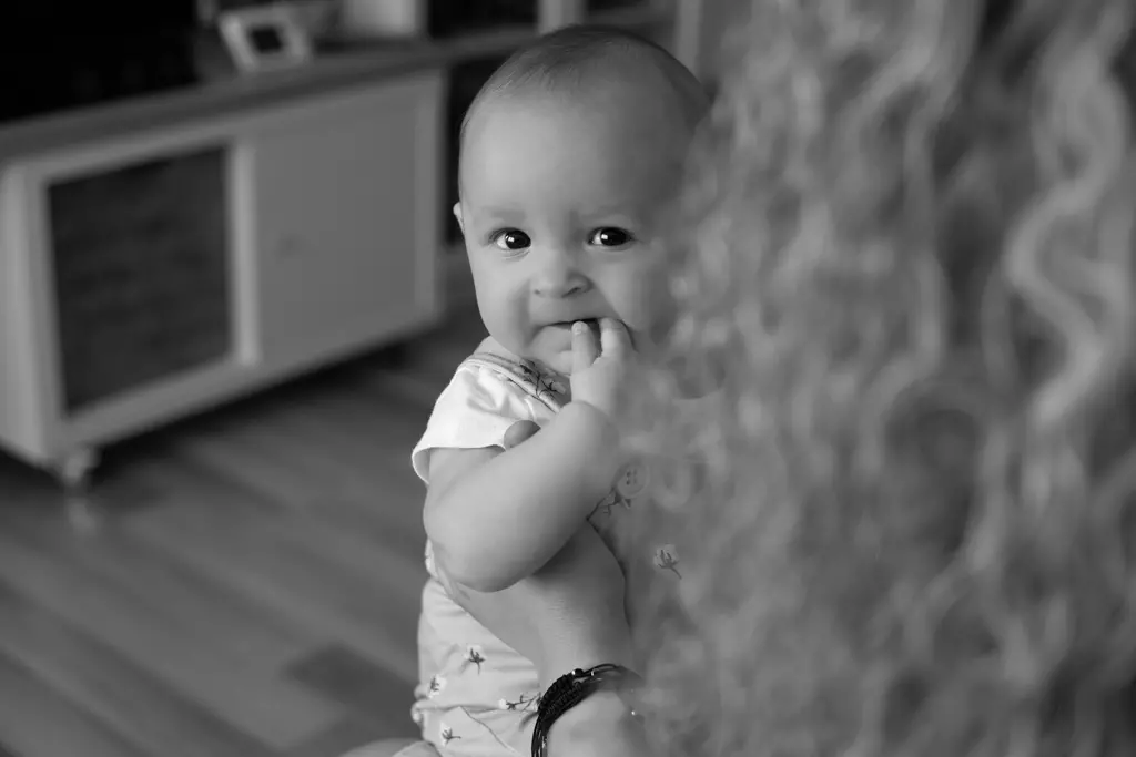 Fotografía documental de bebés en Barcelona: Bebé sonriendo en blanco y negro, mirada curiosa.