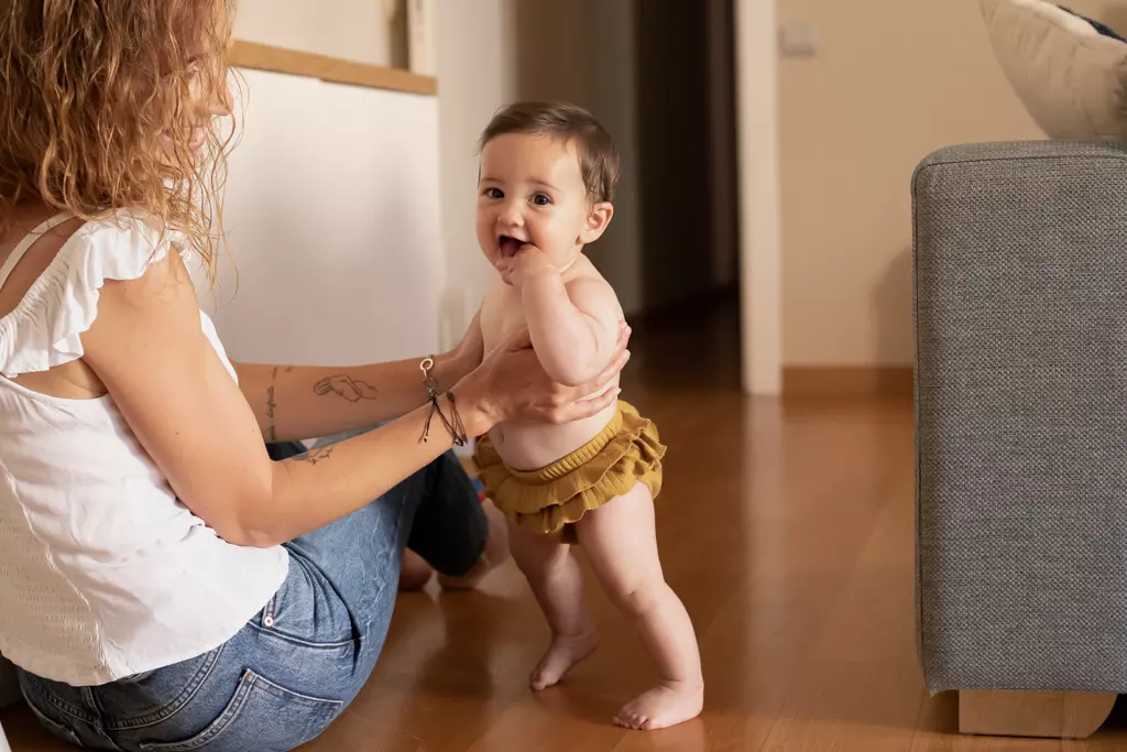 Fotografía de bebés y familia en Barcelona: Madre interactuando con su bebé de pie.