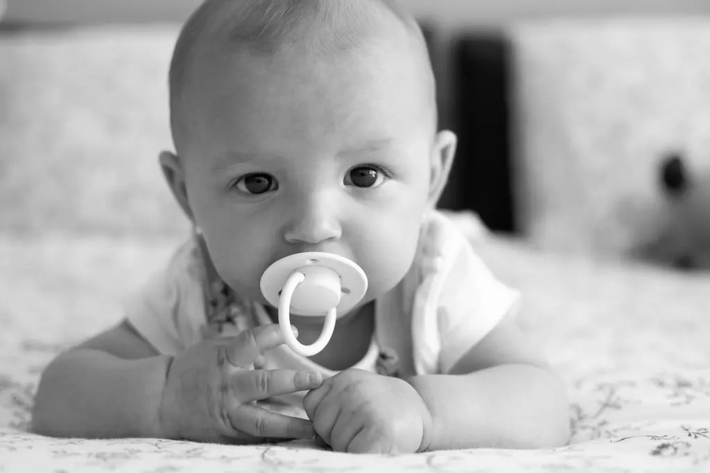 Fotografía de bebés en Barcelona: Bebé boca abajo con chupete, desarrollo del primer año.