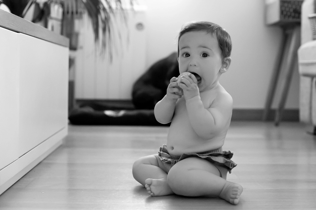 Fotografía de bebés en Barcelona: Bebé sentado explorando en sesión en blanco y negro.