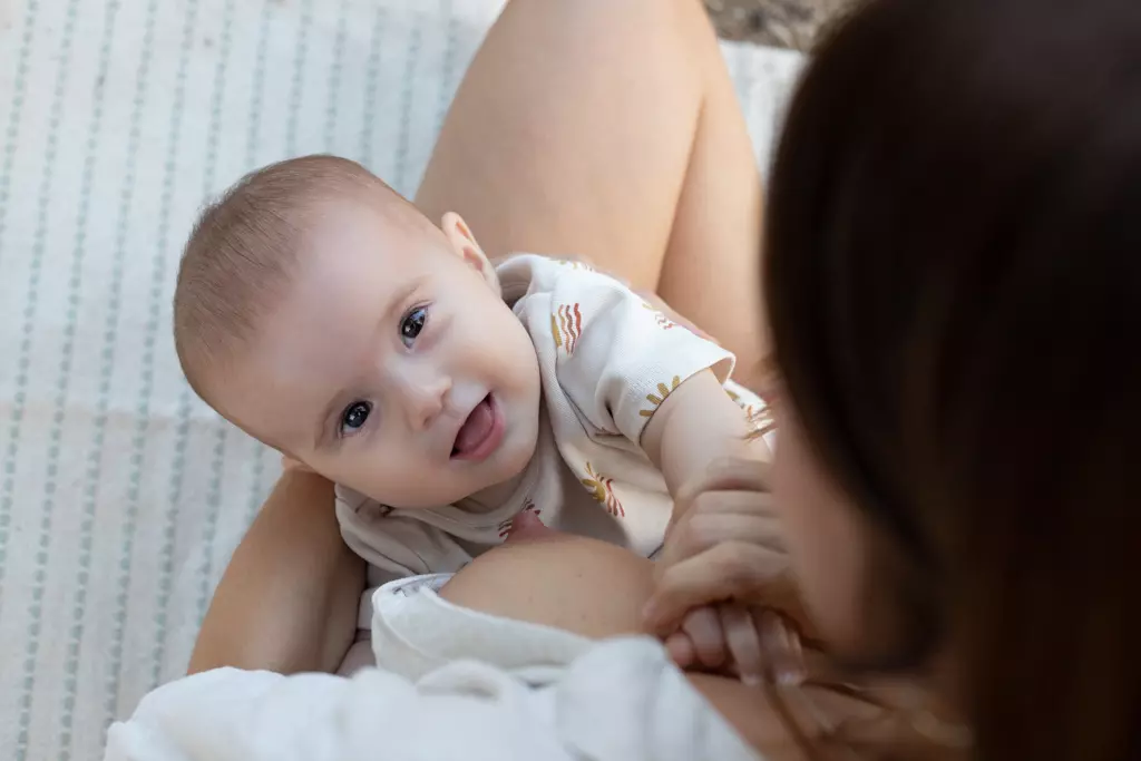 Fotografía de bebés en Barcelona: Bebé sonriendo en brazos de su madre, alegría.
