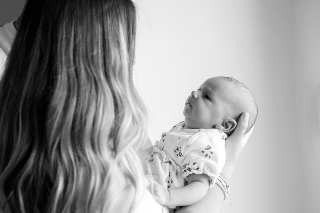 Fotografía de familia en Barcelona: Detalle de madre sosteniendo a su bebé, vínculo.