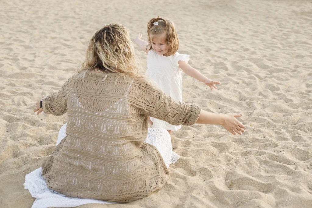 Abrazos entre madre e hija en sesión infantil en la playa de Barcelona