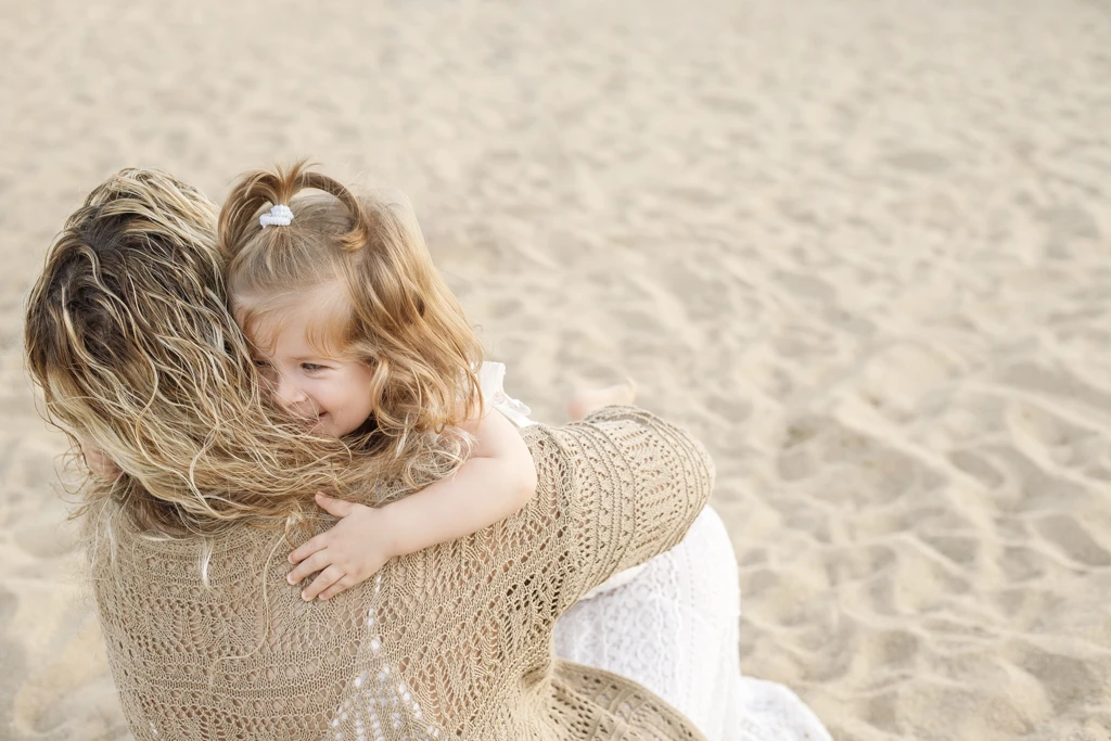 Abrazos entre madre e hija en sesión familiar en la playa de Barcelona
