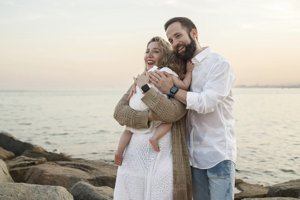 Familia disfrutando en la playa durante sesión fotográfica infantil al atardecer.