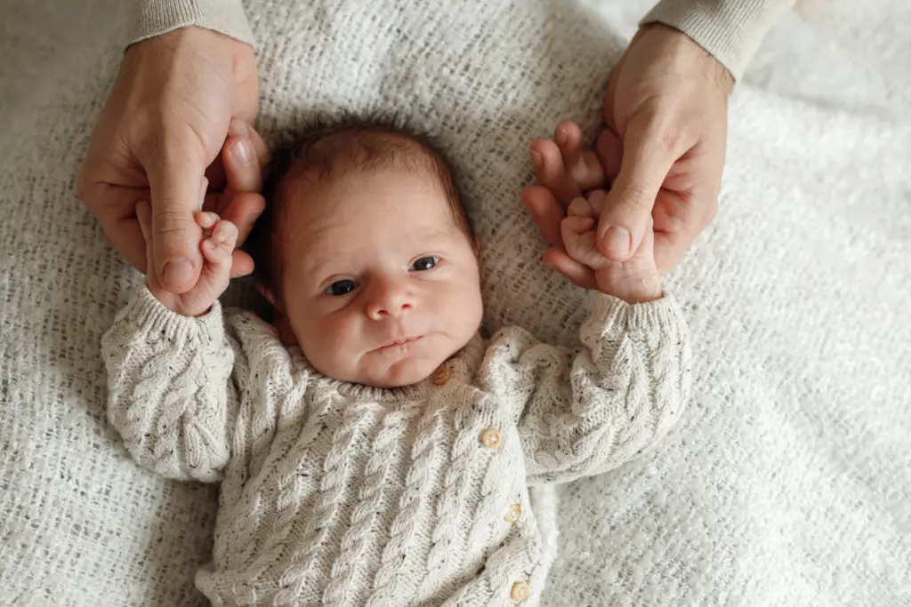 Primer plano de las manos de un recién nacido sostenidas por las de su madre durante una sesión de fotos newborn en Barcelona.