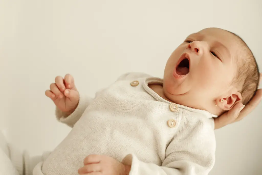 Momento espontáneo de un bebé recién nacido bostezando en su sesión de fotos newborn en Barcelona, mostrando naturalidad.