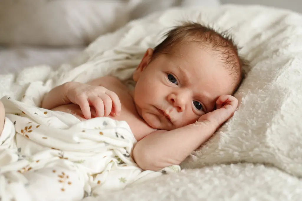 Bebé recién nacido durmiendo plácidamente sobre una manta en sesión fotográfica en domicilio en Barcelona.