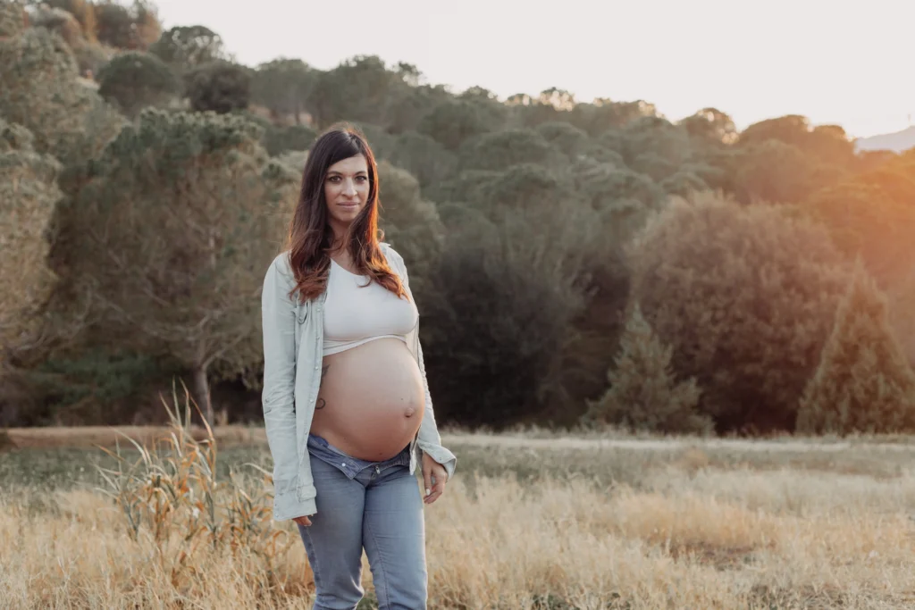 Retrato natural de embarazo con luz suave en exteriores Mujer embarazada de pie posando al atardecer en el campo de Barcelona