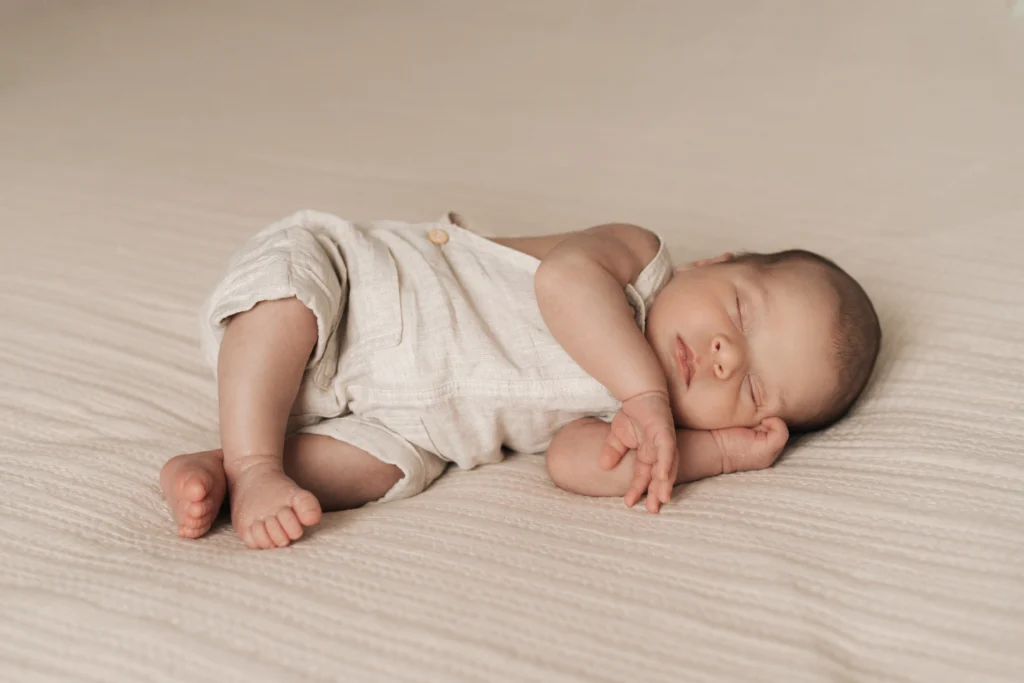Recién nacido dormido sobre fondo blanco durante sesión relajada