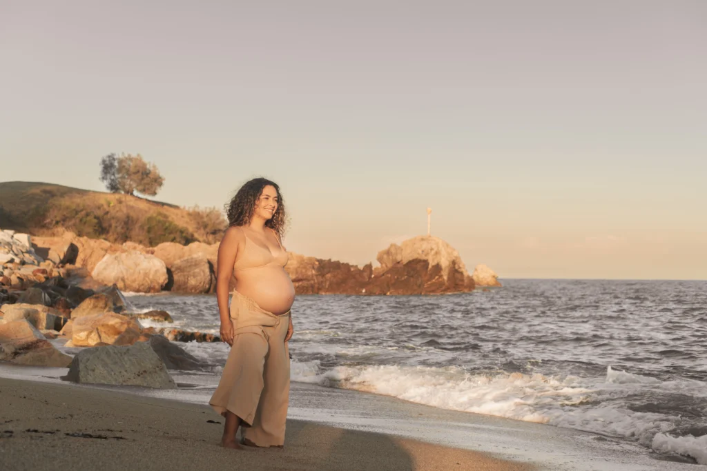 Reportaje de embarazo en la playa al atardecer: la dulce espera frente al mar. Sesión fotográfica de maternidad en exteriores de playa natural cerca de Barcelona