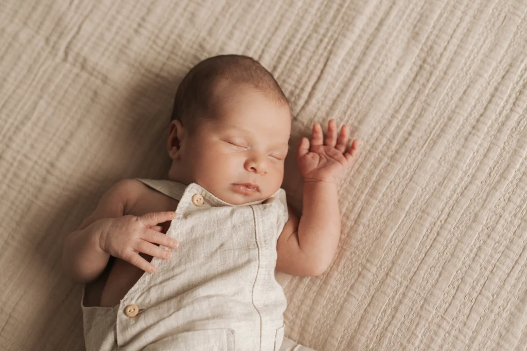 Bebé tumbado sobre manta natural durante sesión newborn en casa