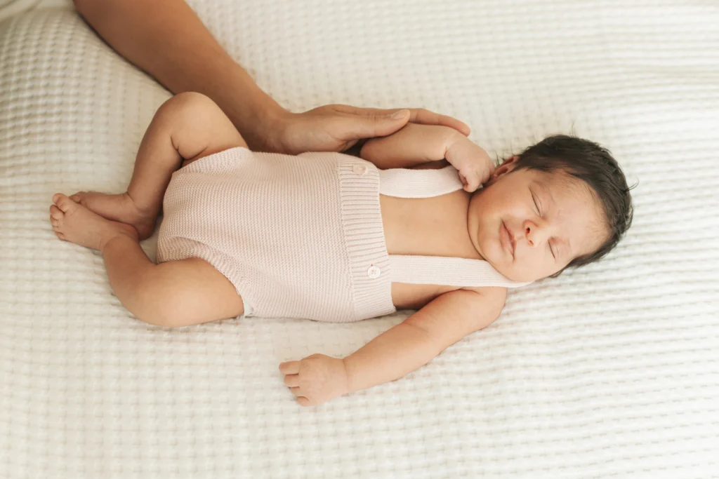 Detalle de bebé dormido con las manos de sus padres acariciándolo