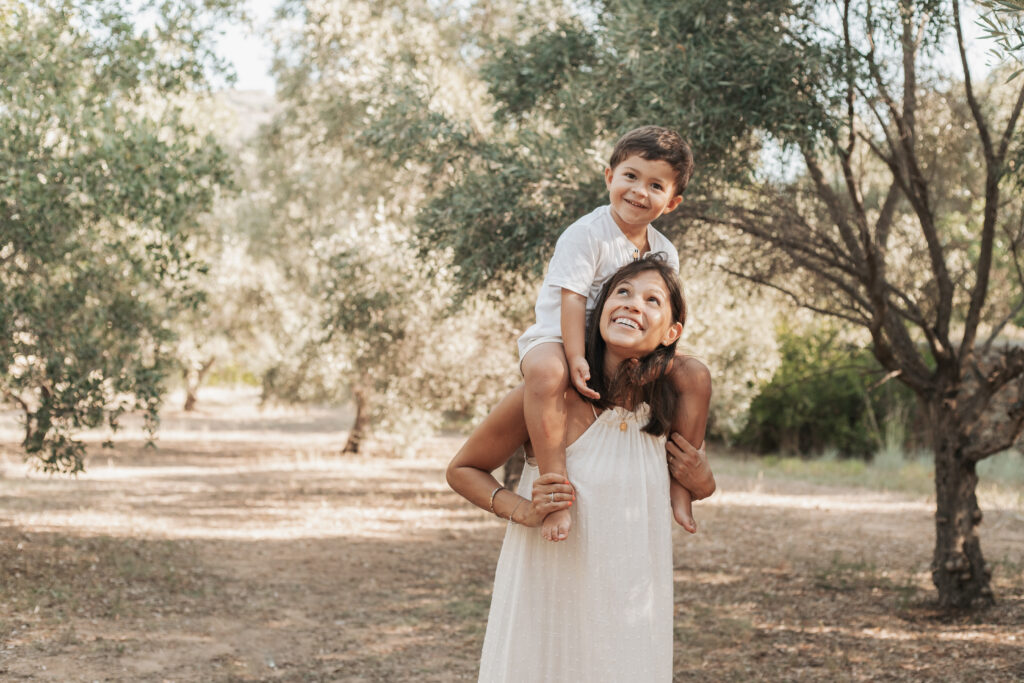 Madre paseando con su hijo sentado sobre los hombros en una sesión fotográfica por el Día de la Madre en la montaña cerca de Barcelona