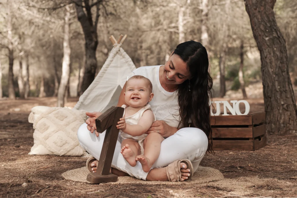 Bebé celebrando su primer cumpleaños con su madre en una sesión de fotos de cumpleaños.