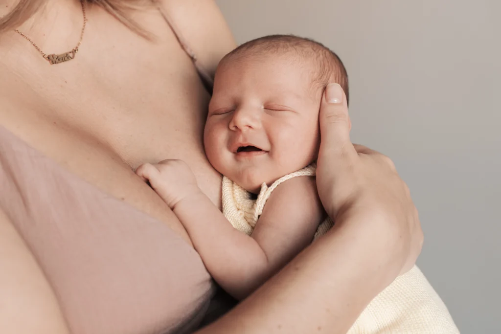 Sesión de fotos newborn natural en Barcelona con bebé sonriendo mientras descansa en el pecho de su madre.