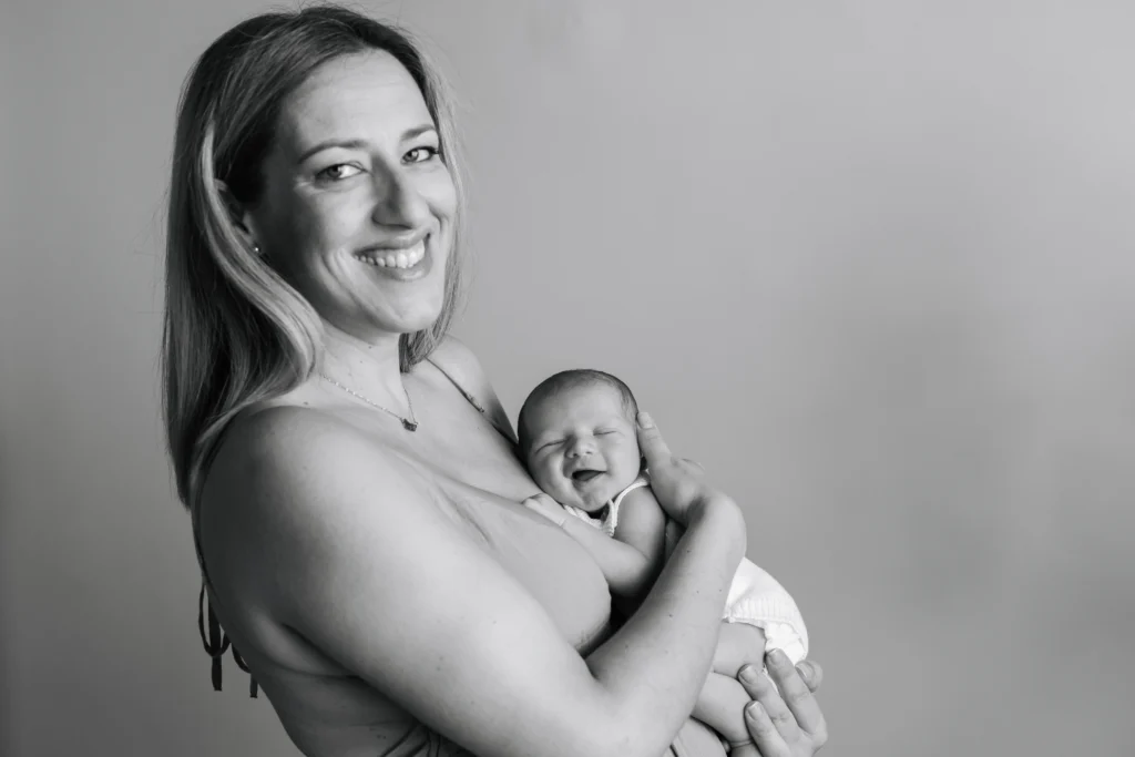Retrato de maternidad y recién nacido con estilo minimalista y luz natural en estudio fotográfico de Barcelona.