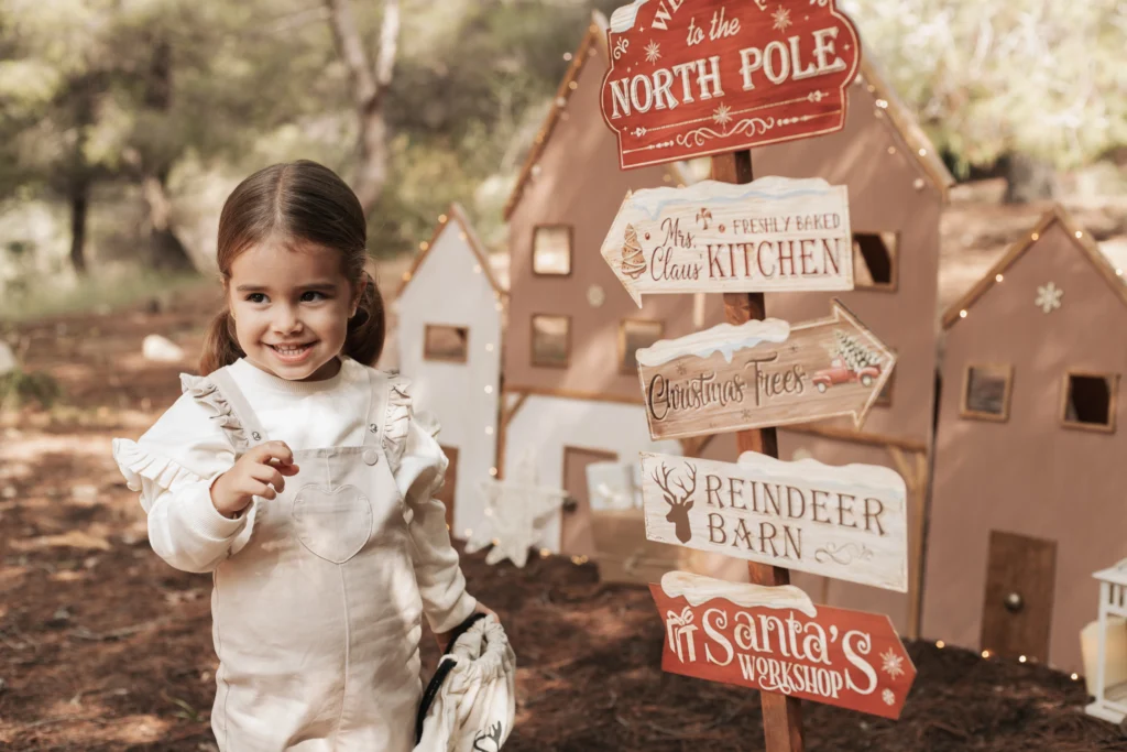 Detalle de reportaje fotográfico infantil navideño en Barcelona con señal del Polo Norte y ambiente festivo natural.