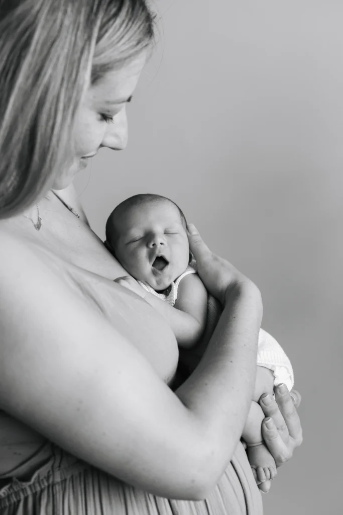 Fotografía newborn en blanco y negro de madre abrazando a su bebé recién nacido dormido en una sesión natural.