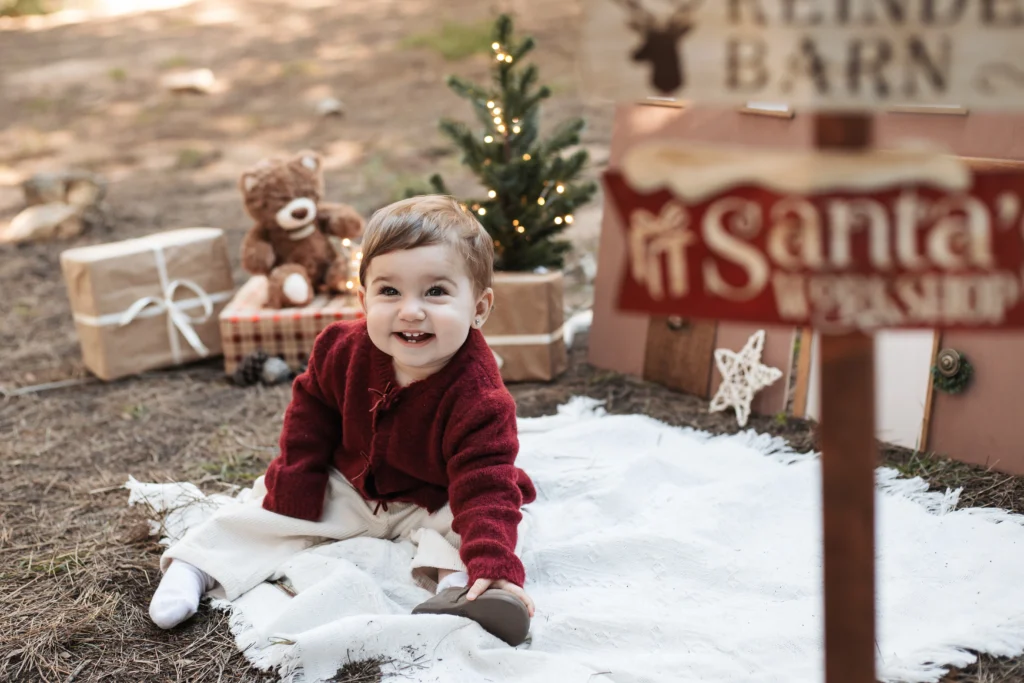 Fotografía infantil de Navidad en Barcelona: sesión exterior con luces, abeto y carteles del Polo Norte.