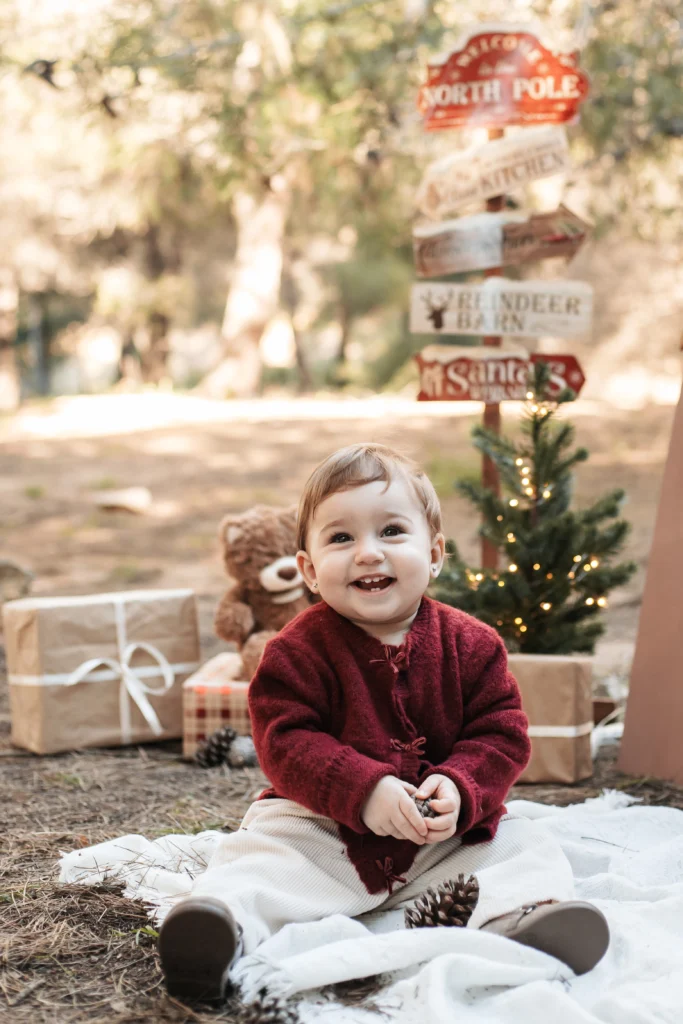 Fotografía infantil de Navidad en Barcelona: bebé sentado en set de exterior con árbol de luces y regalos.