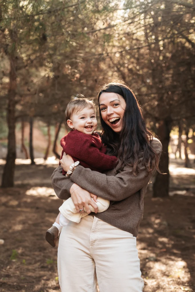 Sesión de fotos de Navidad familiar en exterior Barcelona: madre e hijo abrazados en entorno natural.