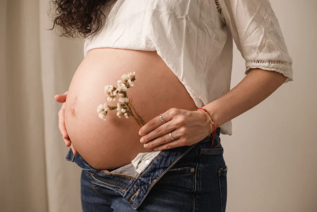 Retrato artístico de embarazada en blanco y negro: poses elegantes en estudio de maternidad. Embarazada sosteniendo ramo de flores secas en estudio de fotos Barcelona.