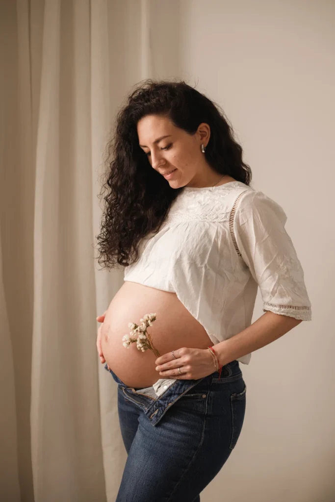Sesión de maternidad individual en estudio: delicadeza y estilo natural con flores. Embarazada en el estudio durante sesión de fotos de maternidad en Barcelona.