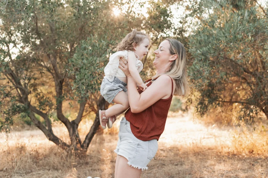 Fotografía familiar íntima en Barcelona: primer plano de madre e hija pequeña sonrientes y cariñosas en la naturaleza.