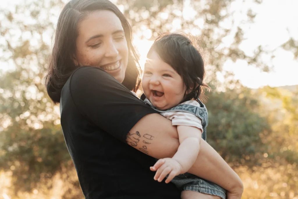 Fotografía familiar en exteriores en Barcelona: Madre e hijo riendo abrazados al atardecer