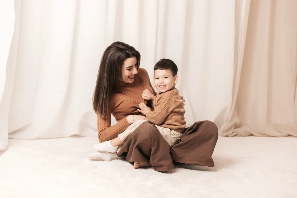 Sesión fotográfica del Día de la Madre - Saray Ruiz Fotografía Madre e hijo riendo juntos en una sesión fotográfica del Día de la Madre en estudio en Santa Coloma de Gramenet. Estilo natural y cálido.