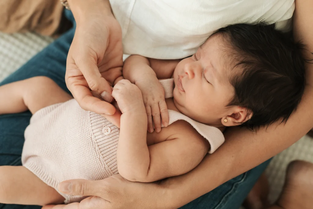 Recién nacido dormido en brazos de su madre, fotografía newborn lifestyle en casa