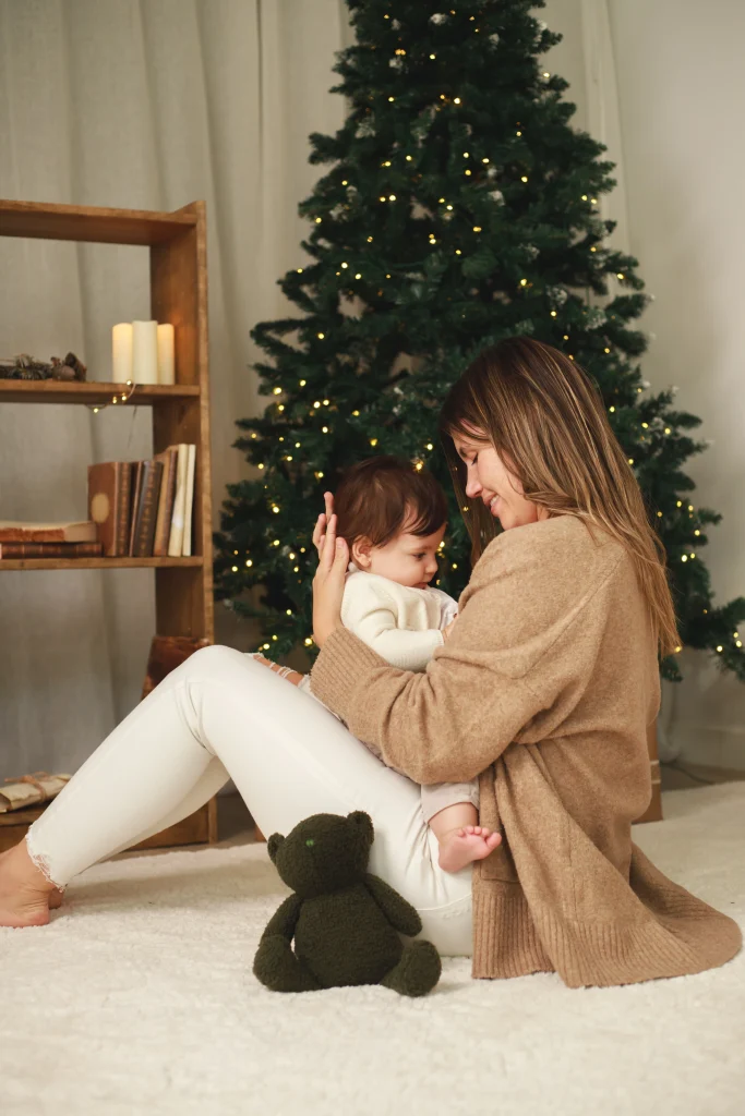 Sesión de fotos de Navidad familiar en Barcelona - madre con su bebé frente al árbol navideño