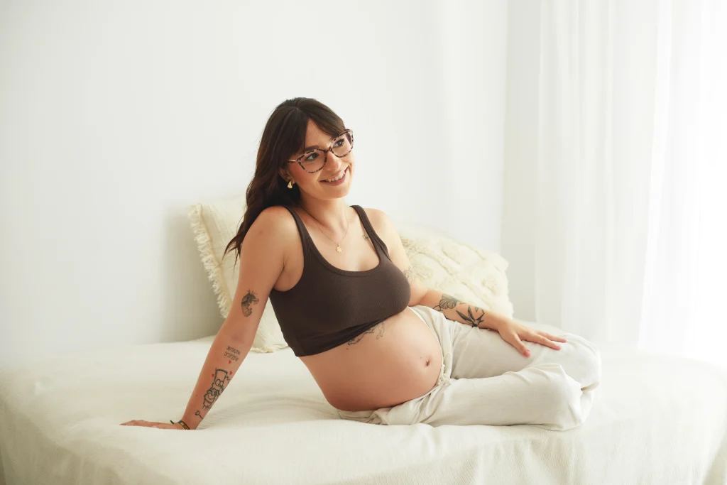 Fotografía de embarazo en estudio en Barcelona, mujer embarazada sentada con luz natural